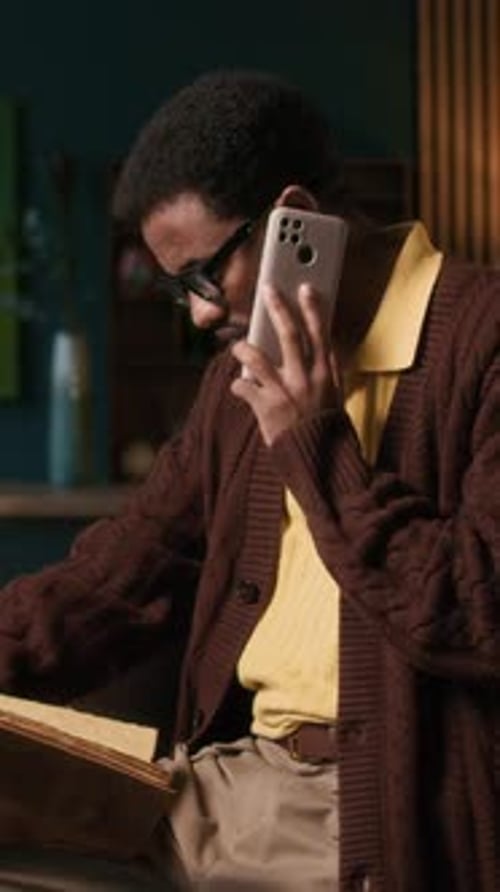 Specialist Discussing Book Details on Mobile Phone at Home