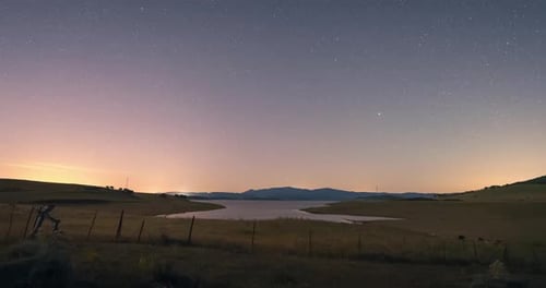 night sky timelapse in rural area Andalusia with lake and mountains as background. Foreground of gra
