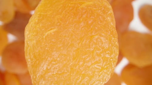 Dried apricot falls onto other apricots, top view, in super slow motion. Macro zoom.