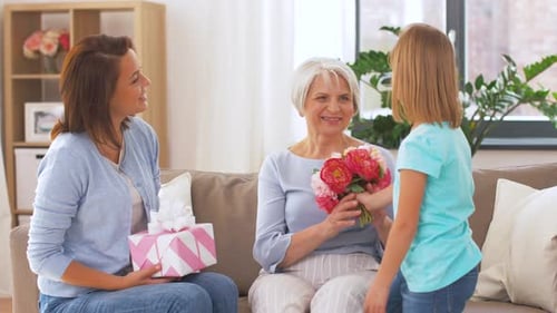 Three Generations Presenting Flowers and Gifts Indoors