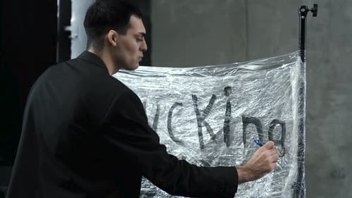 männlicher Künstler malt ein Banner mit einer Pinselinschrift Ficken