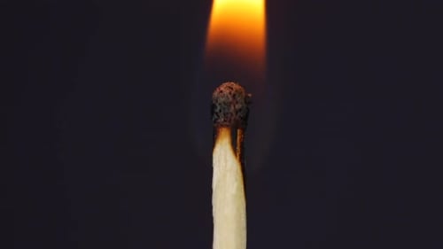 Hand igniting matches close up macro shot captured in front of black background in slow motion at 12