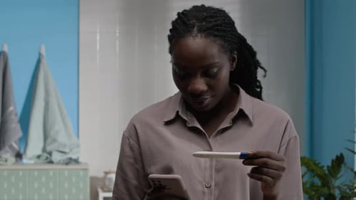 Woman Smiles with Positive Pregnancy Test in Bathroom