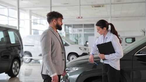 Man and Woman Discuss Car in Showroom