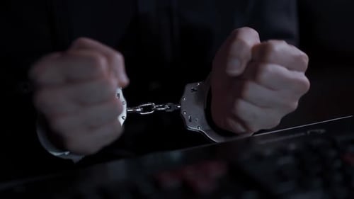 Hands Wearing Handcuffs Above Keyboard