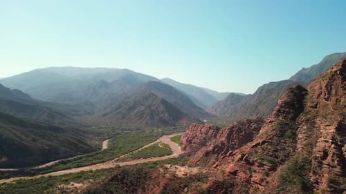 Aerial view drone flying over scenic red rocky mountains with a clear blue sky.