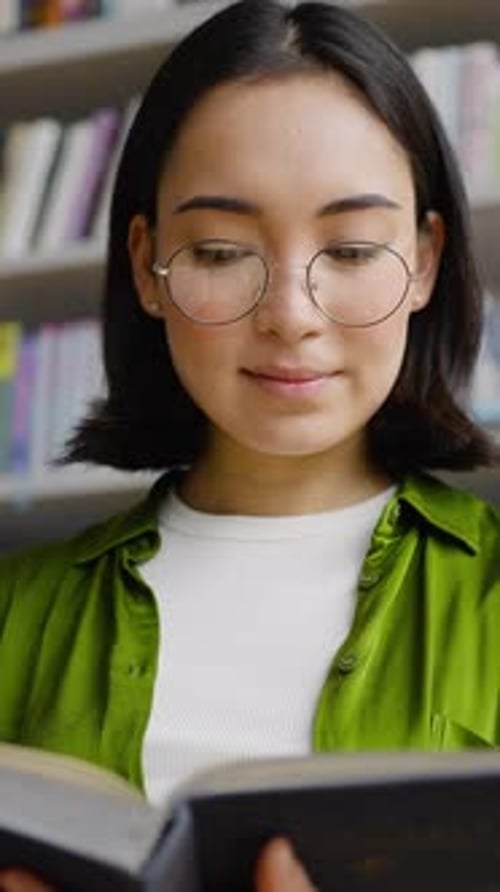 Young Female Enjoys Reading Interesting Book in Library