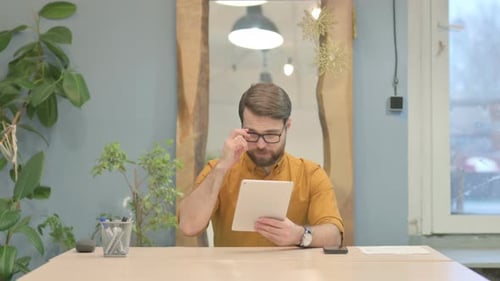 Man Using Tablet at Desk in Bright Office