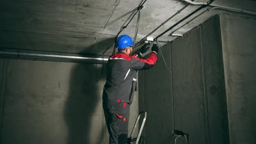 Electrician Standing on Ladder Working on Wiring