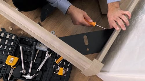 Man Assembling Furniture Frame with Screwdriver