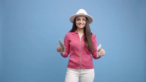Woman Holding Money and Gift in Front of Blue Backdrop