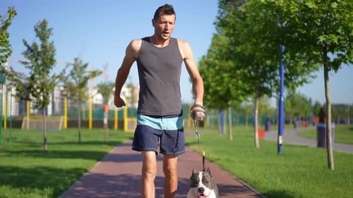 Hombre motivado de tiro panorámico corriendo con perro deteniéndose en el entrenamiento Vista frontal Retrato de