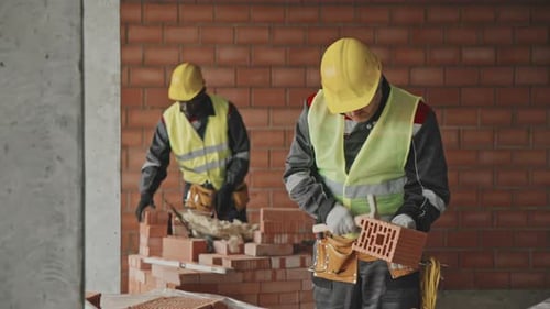 Construction Workers Building Brick Wall on Job Site