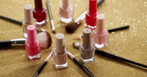 Colorful Nail Polish and Makeup Brushes on Glittery Surface