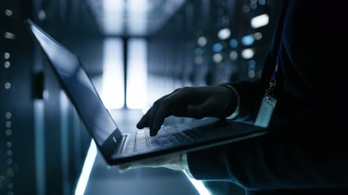 Especialista en TI que trabaja en una computadora portátil, es empleado de un gran centro de datos ultramoderno.