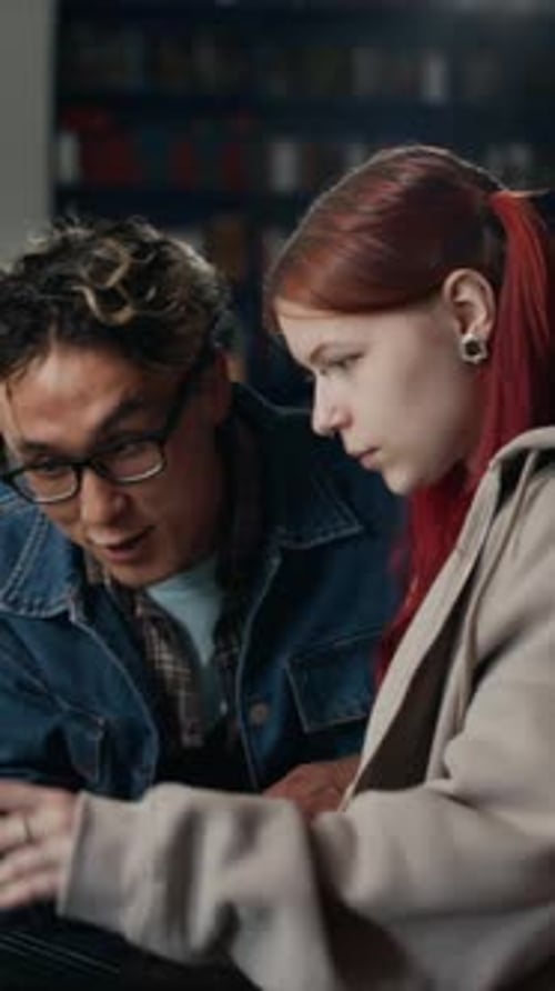Vertical of Diverse Couple of Students Working on Project Together in Library