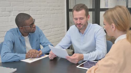 Diverse Team Discussing Charts and Graphs in Office