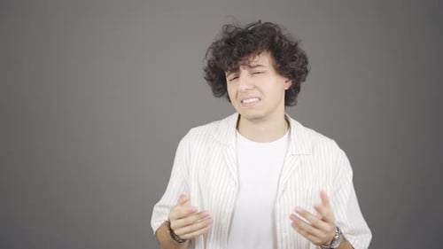 Young Adult Expressing Sadness in Front of Background