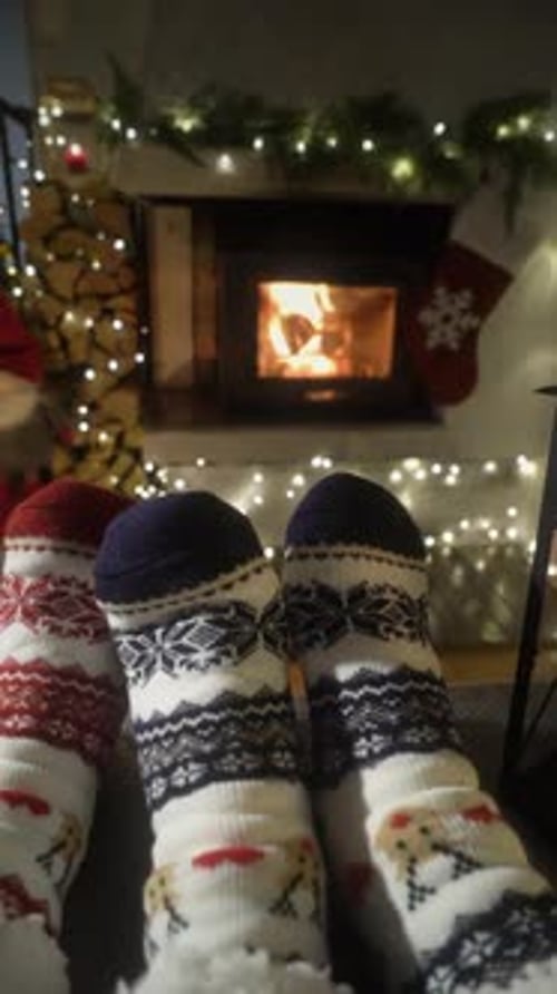Couple Enjoying By Fireplace and Warming Up Their Feet in Woolen Socks with Christmas Tree and