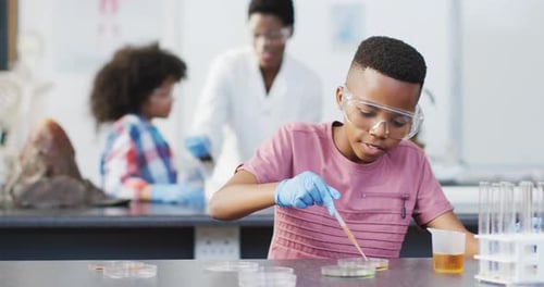 Diverse female teacher and happy schoolchildren having science class in school lab