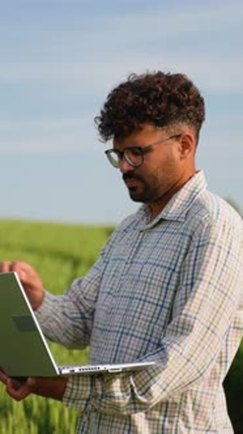 Landwirt verwendet Laptop bei der Montage von Weizenfeldern