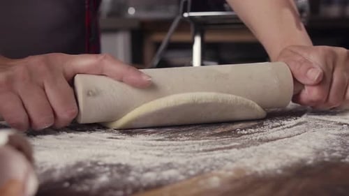 Hands Rolling Dough with Rolling Pin in Kitchen