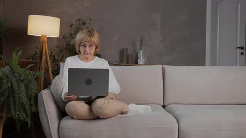 Woman Uses Laptop on Sofa at Home