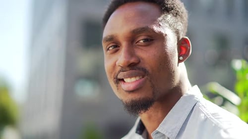 close up portrait happy African American man looking at camera outside. Face of smile young adult