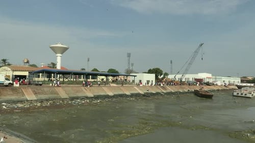 Bandim fishing port at low tide, in the background the control tower and a dredger that cleans the r