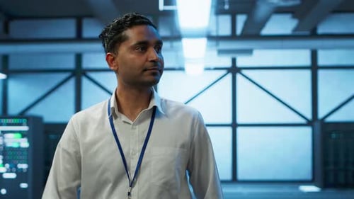 Man Walking in Server Room Wearing Lanyard