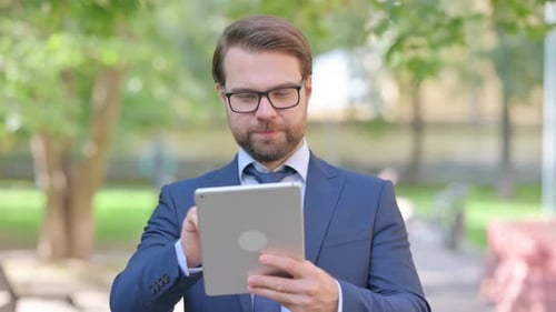 Man Uses Tablet in Urban Park Setting