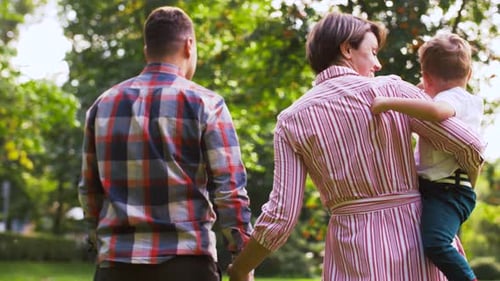Family, Leisure And People Concept - Happy Mother, Father And Little Son Walking At Summer Park