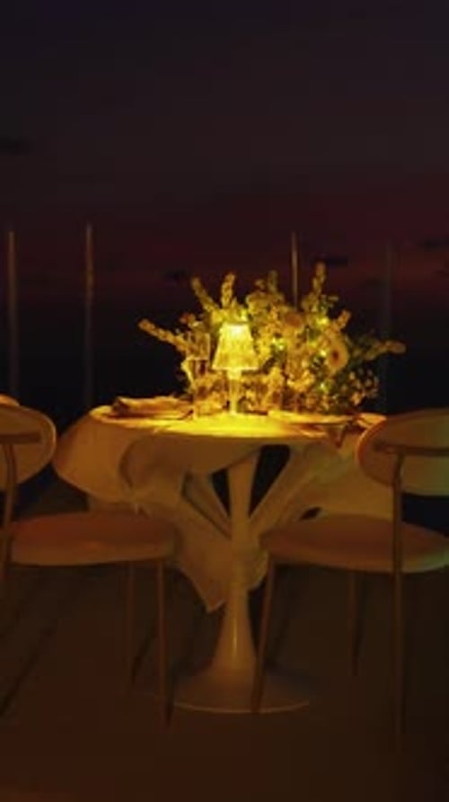 Table for romantic dinner at night served on the outdoor terrace of restaurant with sea sunset view