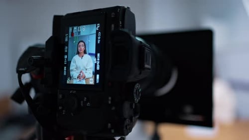 Modern camera display with a female talking recording a video. Blog or vlog creation in studio.
