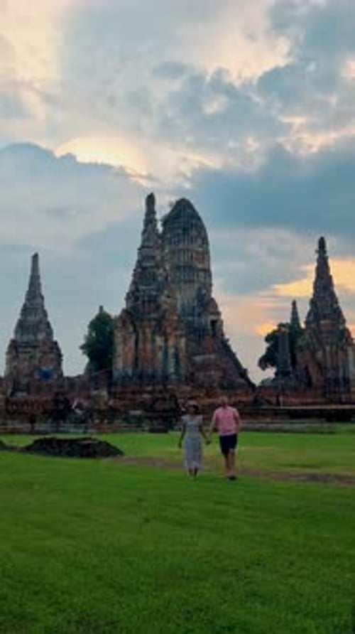 Des hommes et des femmes portant un chapeau visitent Ayutthaya en Thaïlande à Wat Chaiwatthanaram au coucher du soleil