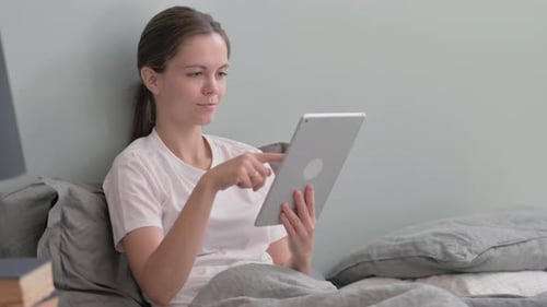 Young Woman Using Tablet While Sitting in Bed
