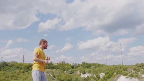 A Man Wearing a Yellow Shirt is Practicing His Boxing Techniques in a Picturesque Park with Lush