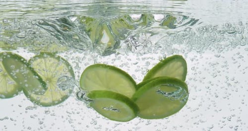 Lime Slices Plunging into Sparkling Water