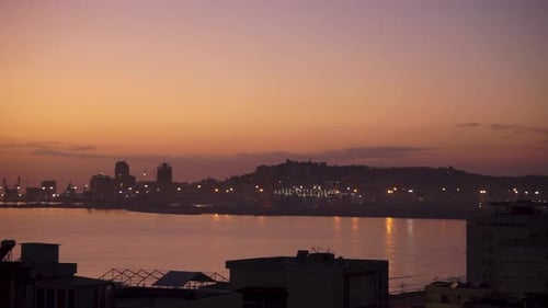 Twilight cityscape timelapse with harbor lights reflecting on water