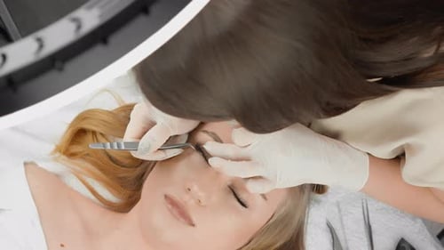 O mestre lashmaker em um luxuoso salão estende cuidadosamente os cílios, dando à mulher uma beleza inigualável