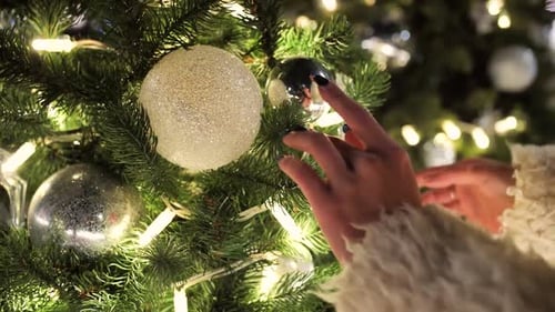 Female Hands Touch a Christmas Tree Closeup Glowing Garlands on New Year's Eve