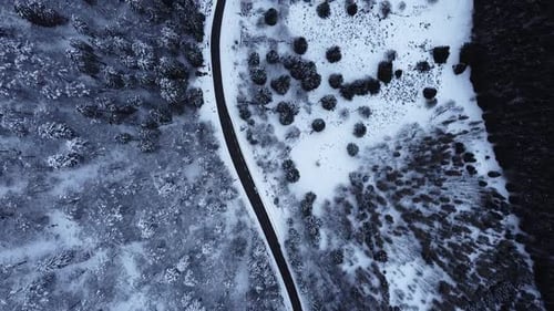 Aerial view of a winding mountain road in winter covered in snow