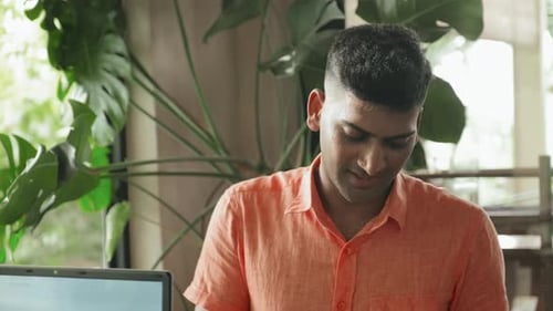 Indian Man Taking Notes and Speaking with Coworker in Cafe