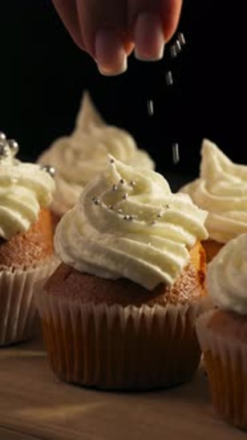 Vertical View Of A Gourmet Cupcake With White Frosting And Shiny Candy Pearls. Close-up Shot