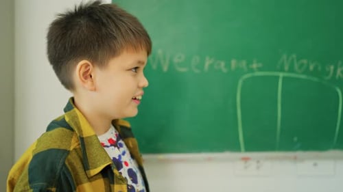 Nahaufnahme Junge schreibt gerne seinen Namen auf Greenboard und buchstabiert auch vor dem Klassenzimmer, der Schule