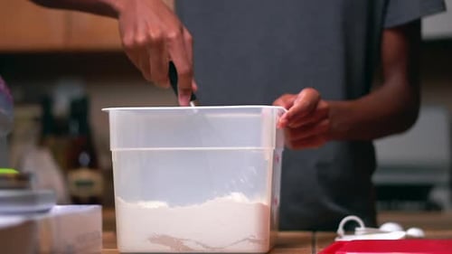 Using a whisk to stir yeast, salt and sugar into flour for a homemade batter recipe - slow motion