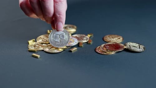 Hand Placing Cryptocurrency Coins and Gold Bars