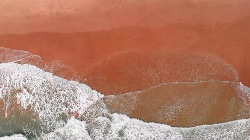 Golden sandy beach and breaking turquoise sea waves, top view