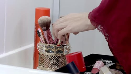 Hand Selecting Makeup Brush in Bathroom