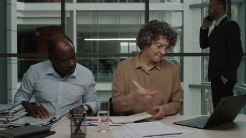 Colleagues Collaborate at Desk in Modern Office